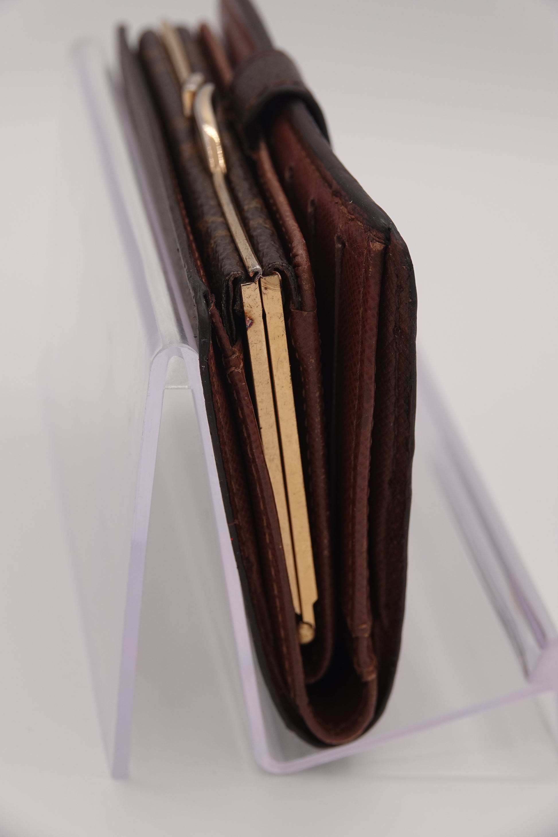 Brown leather wallet with gold accents on a white background