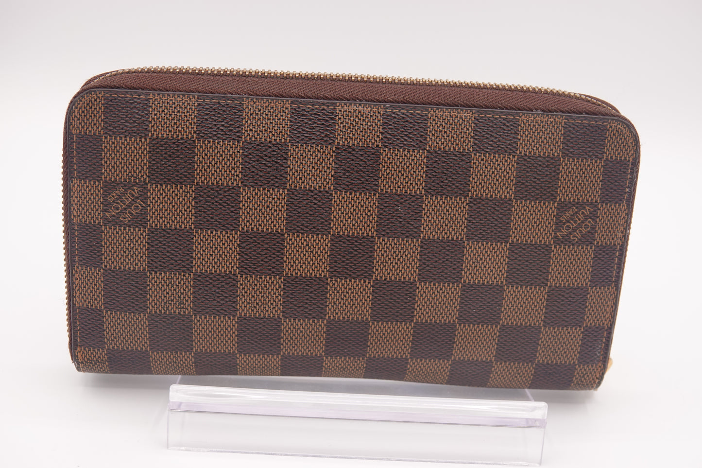 Brown checkered wallet with brand logo on a white background