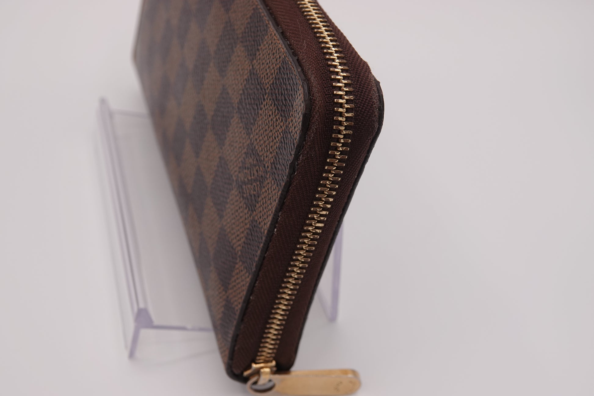 Brown patterned zippered pouch with gold zipper on a white background