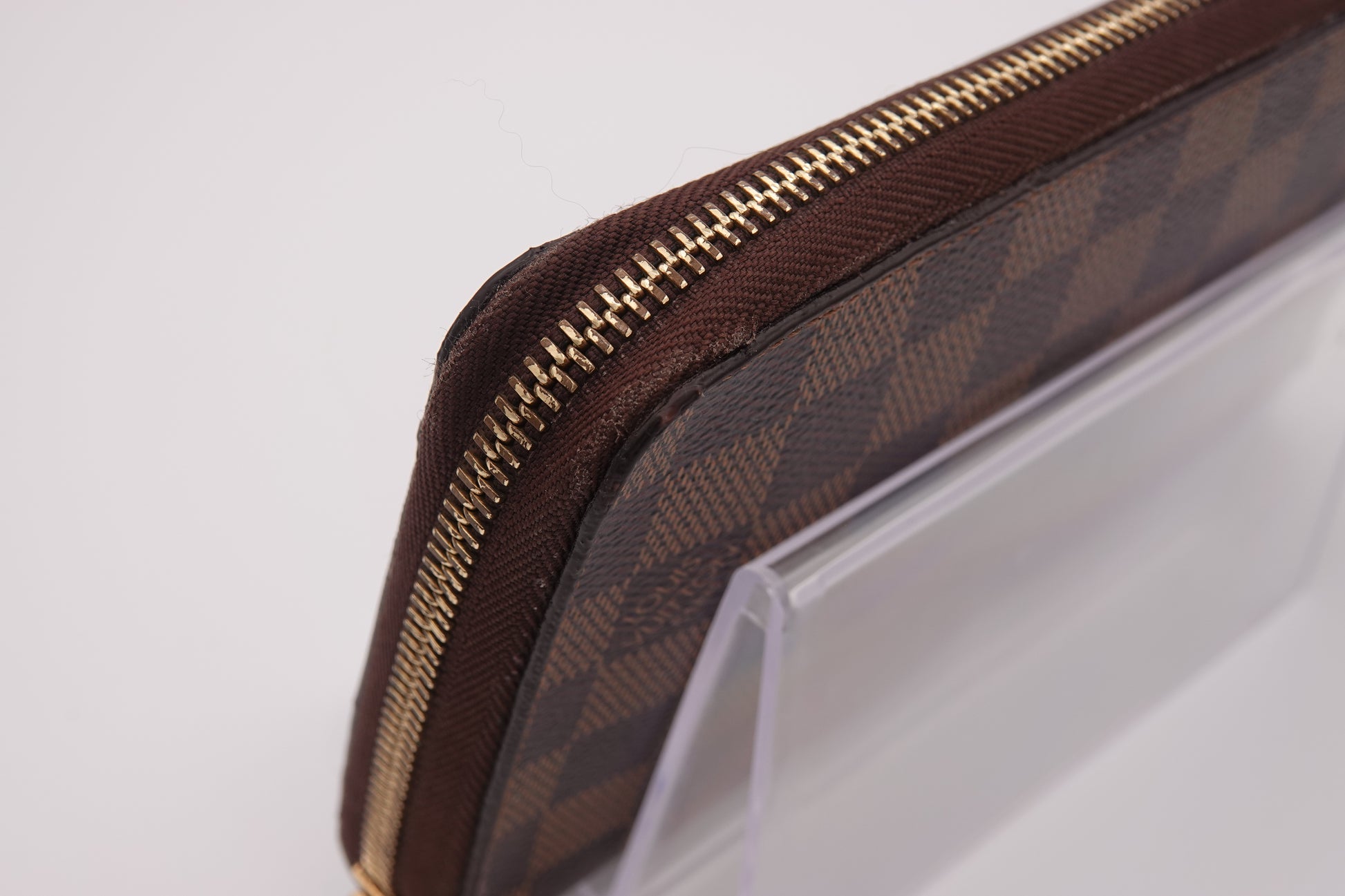 Brown patterned pouch with gold zipper on a white background