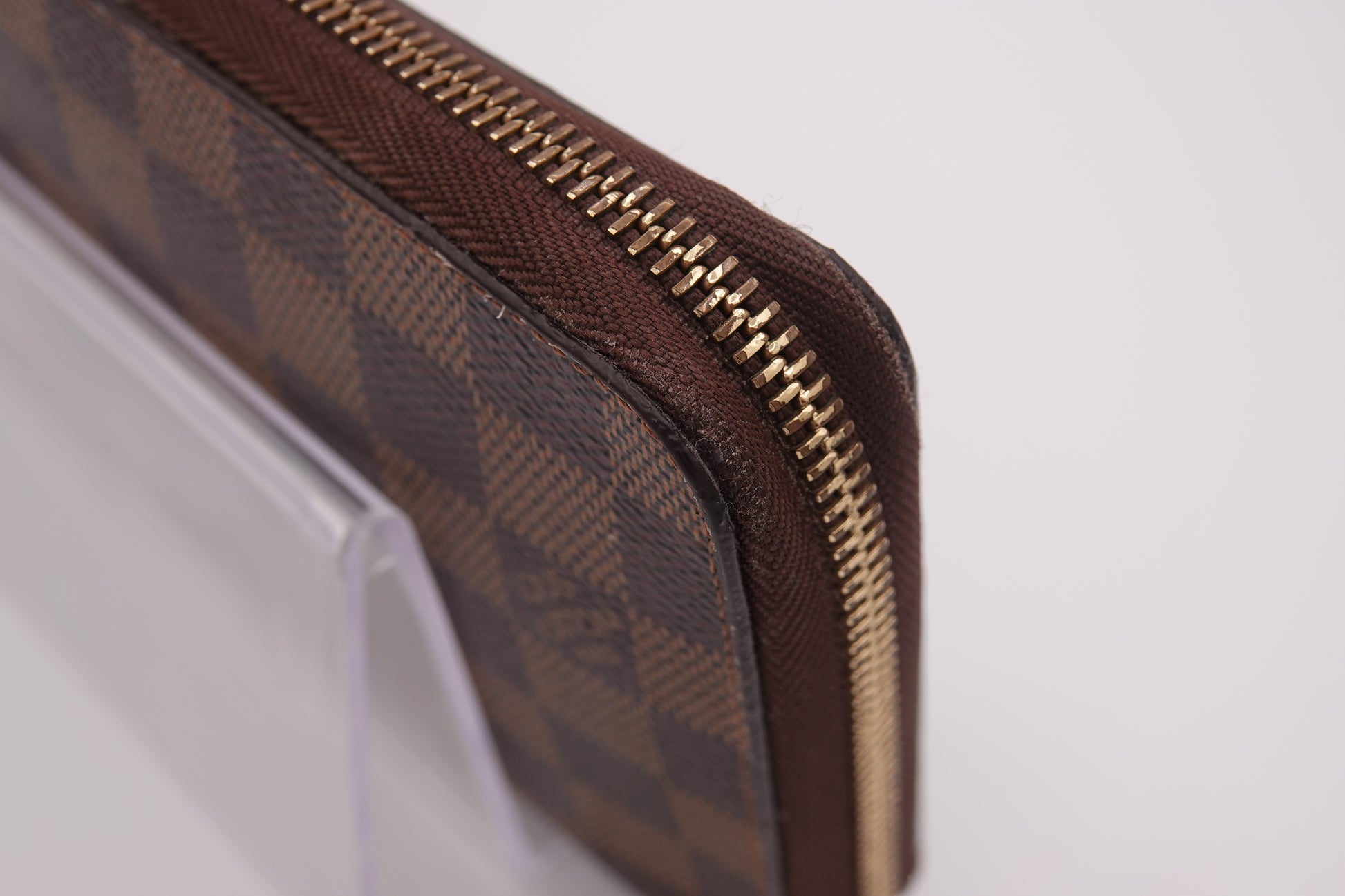 Brown checkered zippered pouch with gold zipper on a white background