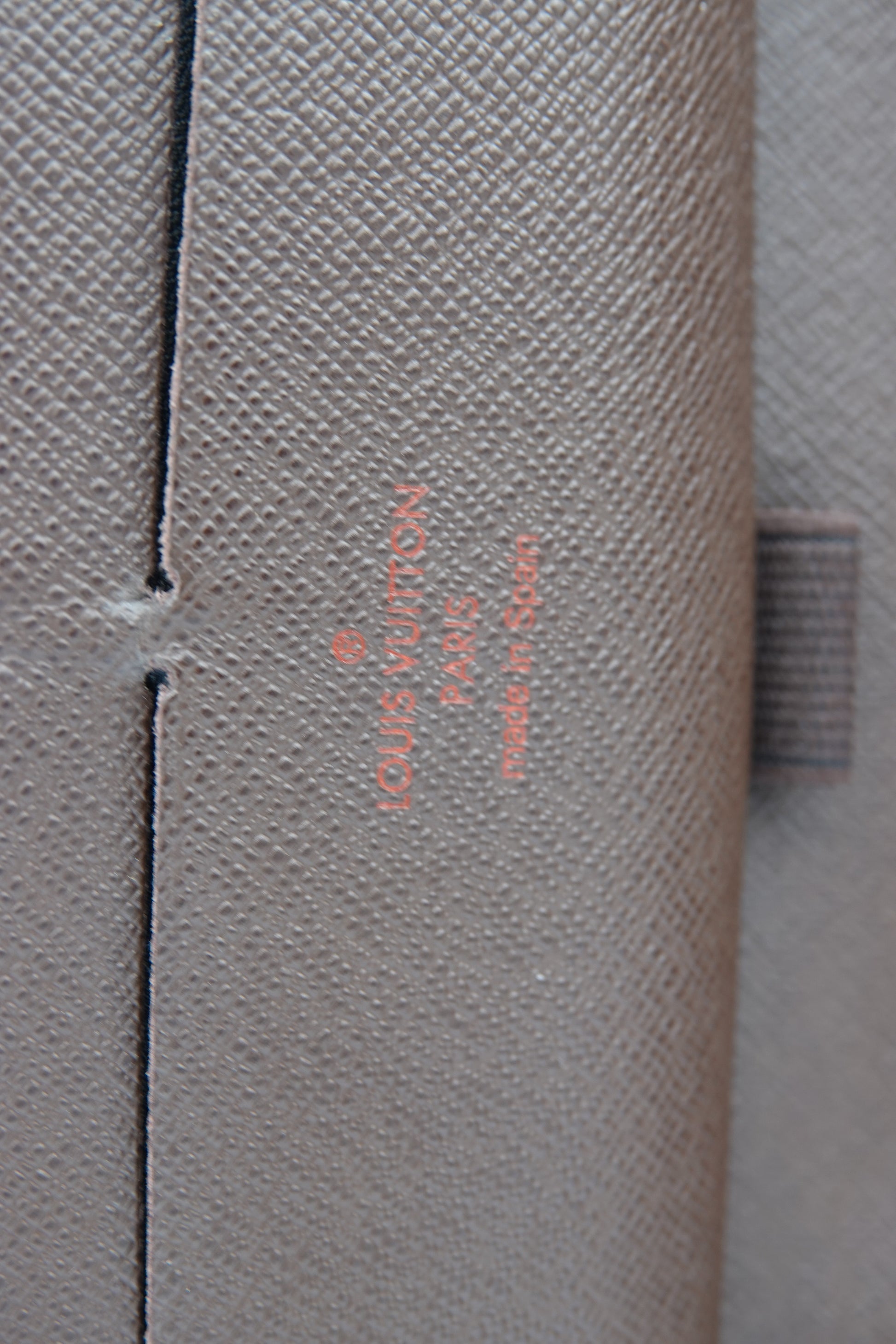 Louis Vuitton suitcase with brand name embossed on a textured surface