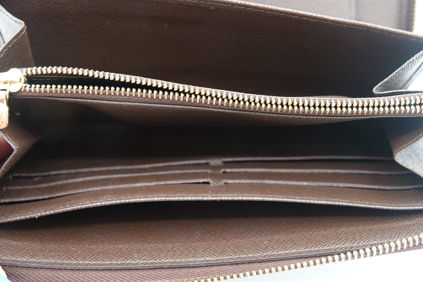Brown leather bag with gold zipper on a neutral background