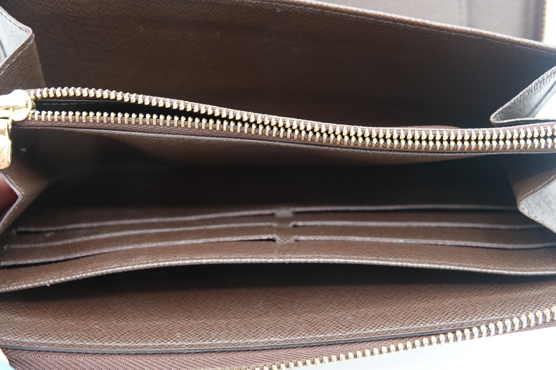 Brown leather bag with gold zipper on a neutral background