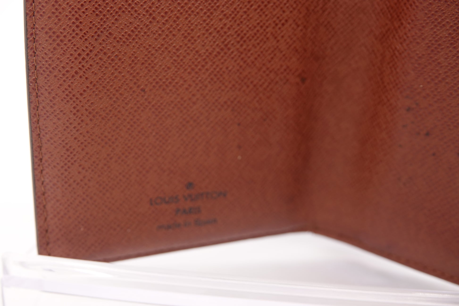 Close-up of a brown leather wallet with 'Louis Vuitton' branding.