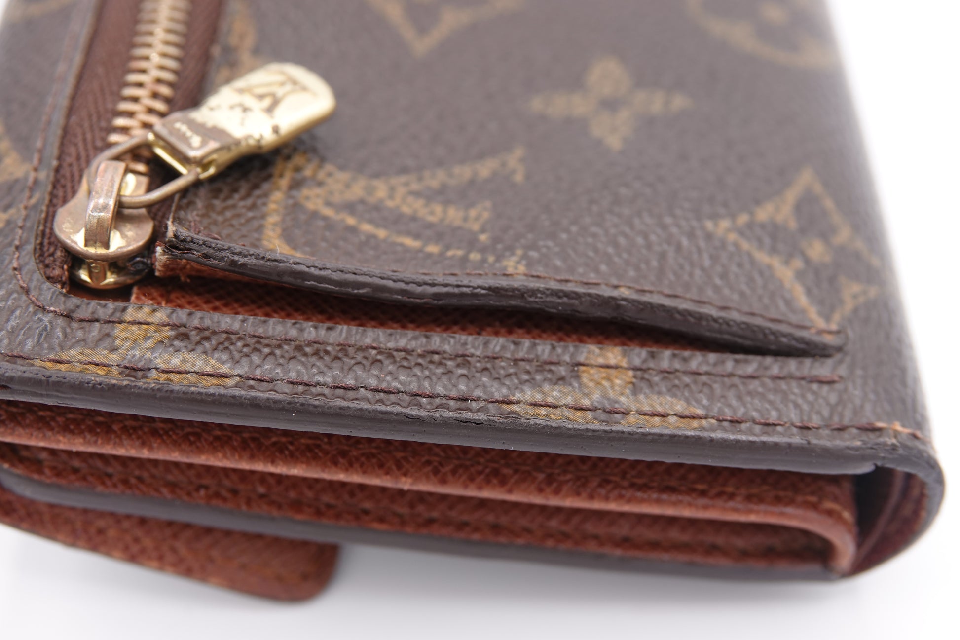Close-up of a brown wallet with gold zipper on a white background
