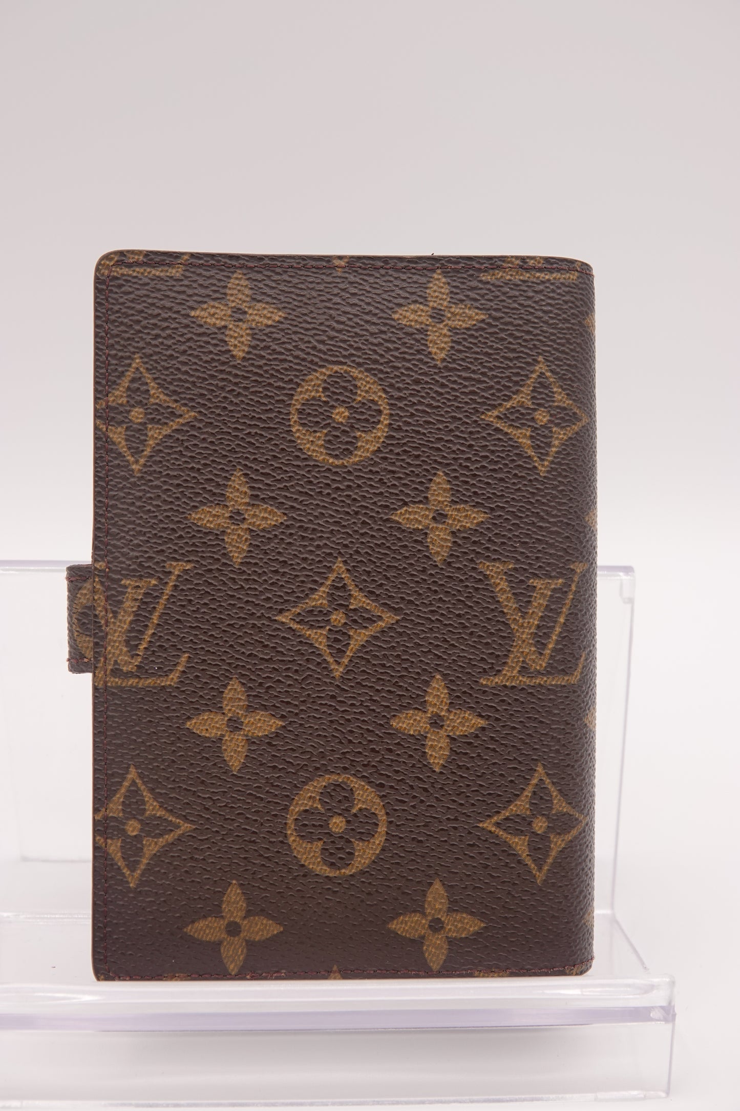Brown wallet with gold monogram pattern on a white background