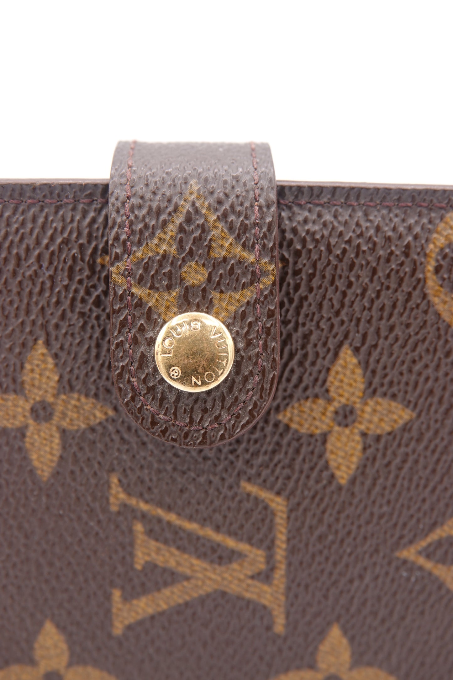 Close-up of a Louis Vuitton wallet with monogram pattern and gold button.