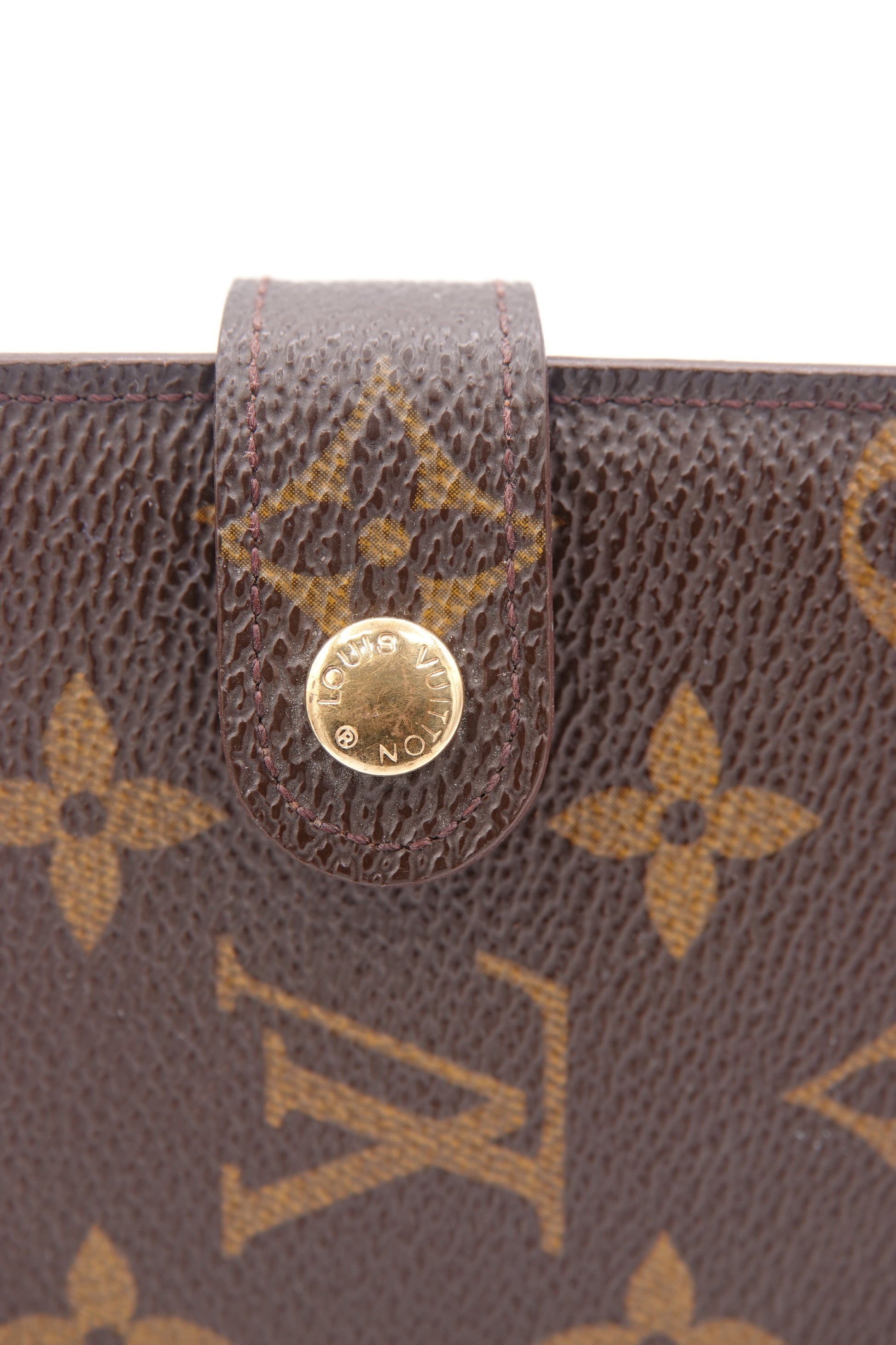 Close-up of a Louis Vuitton wallet with monogram pattern and gold button.