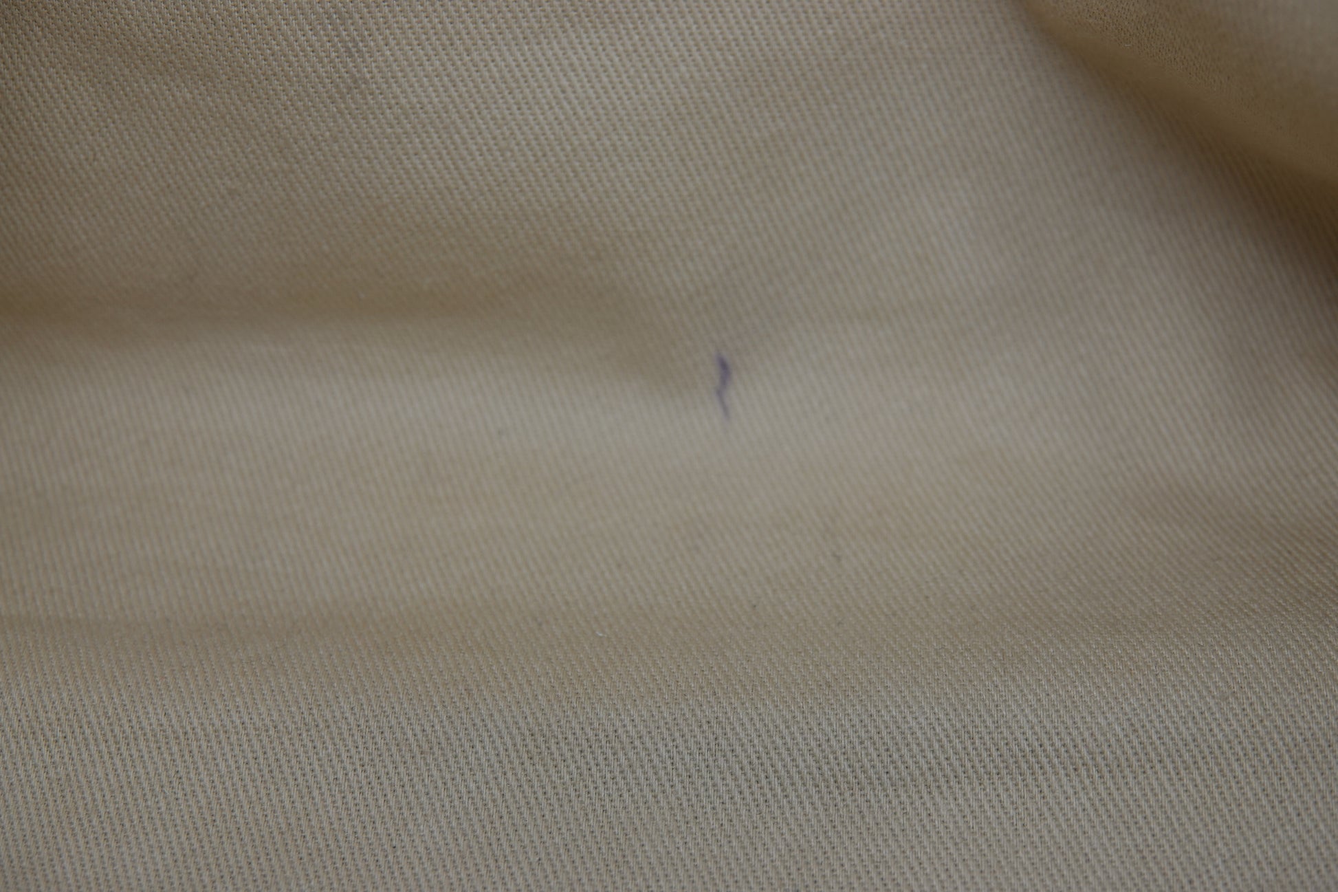 Close-up of beige fabric with a small defect