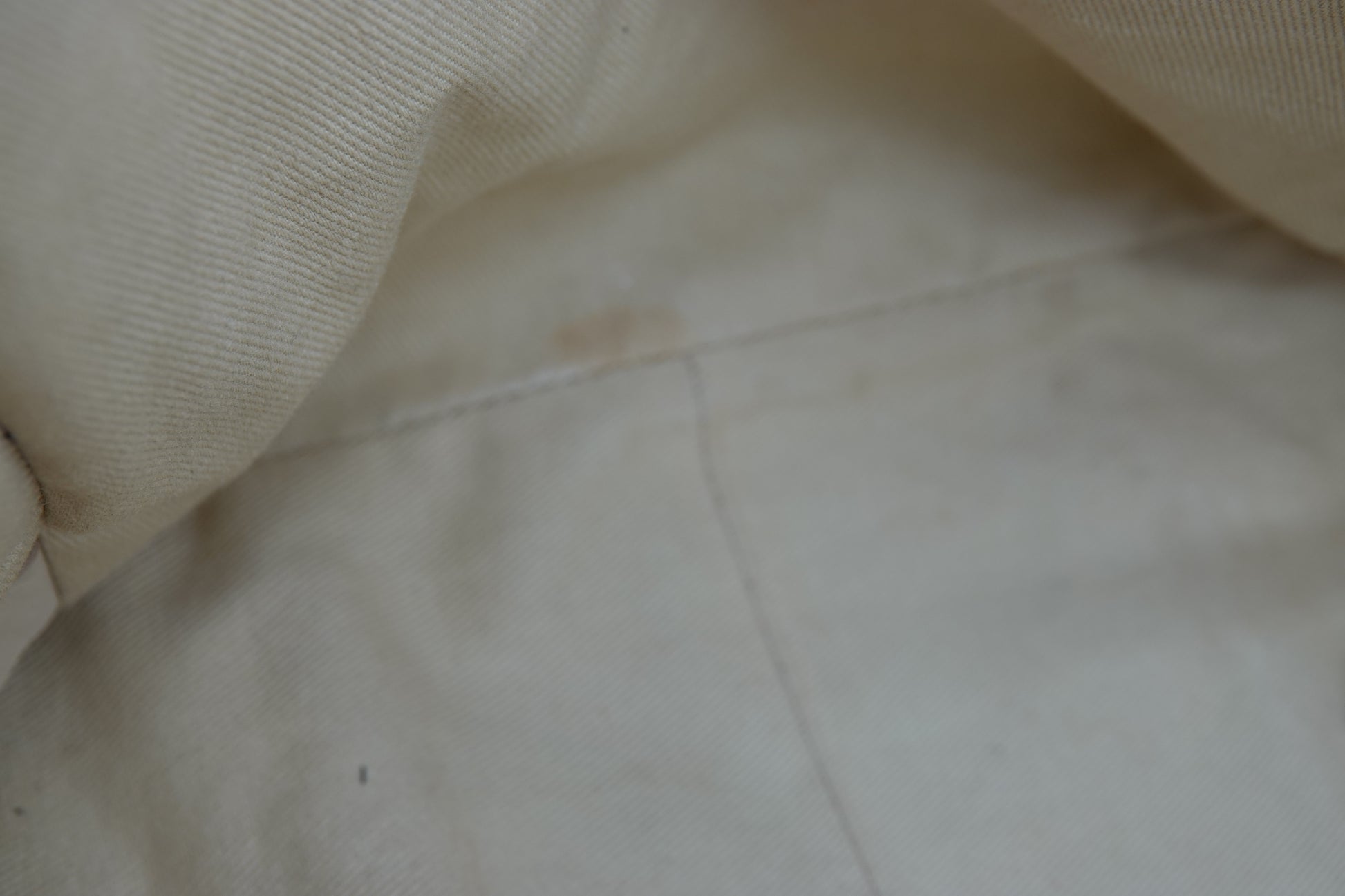 Close-up of beige fabric with a visible stain on a light-colored surface