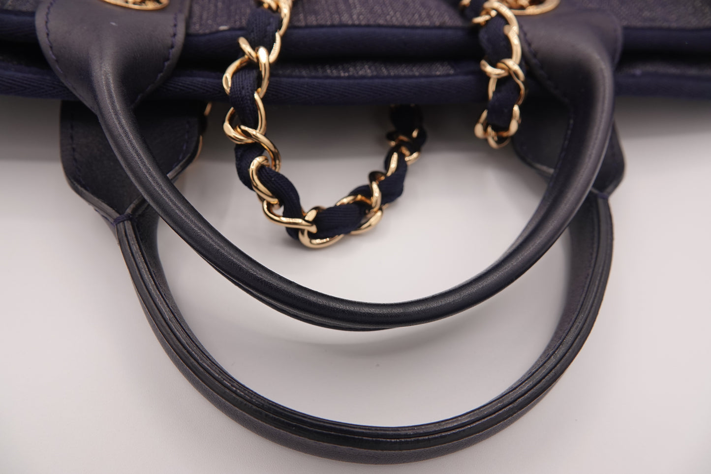 Black handbag with gold chain handle on a light gray background
