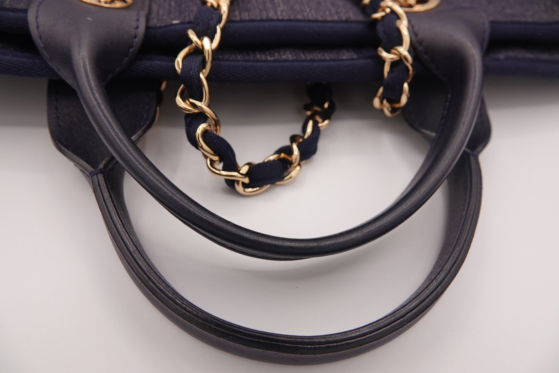 Black handbag with gold chain handle on a light gray background