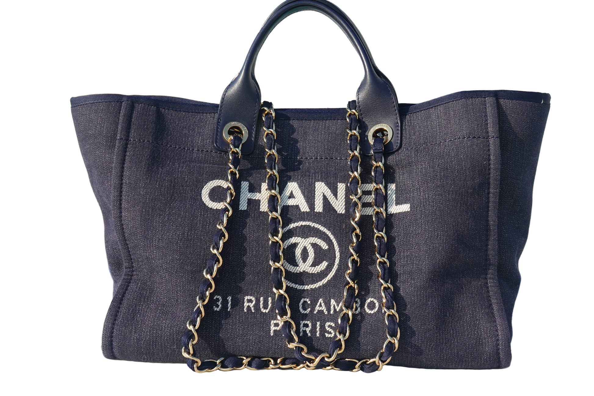 Chanel handbag with gold chain on a reflective surface