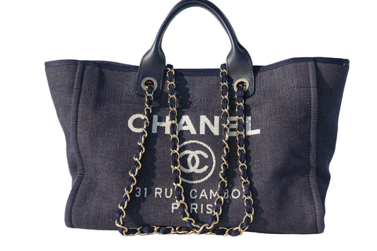 Chanel handbag with gold chain on a reflective surface
