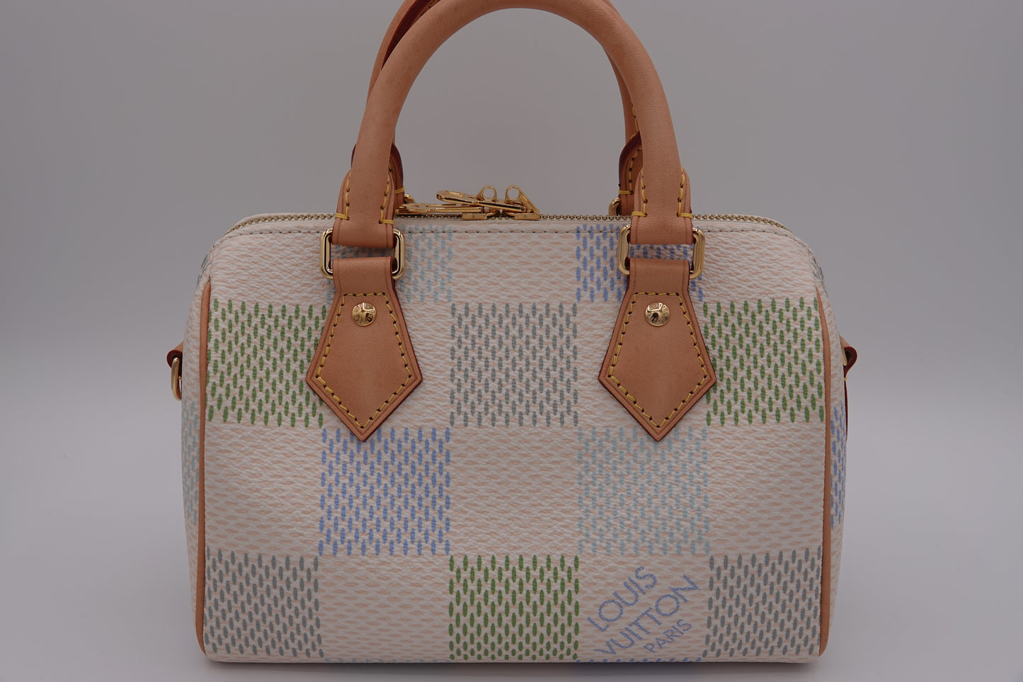 Patchwork handbag with brown leather handles and accents on a gray background