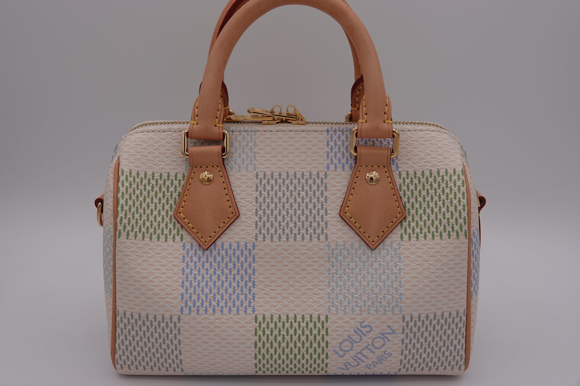 Patchwork handbag with brown leather handles and accents on a gray background