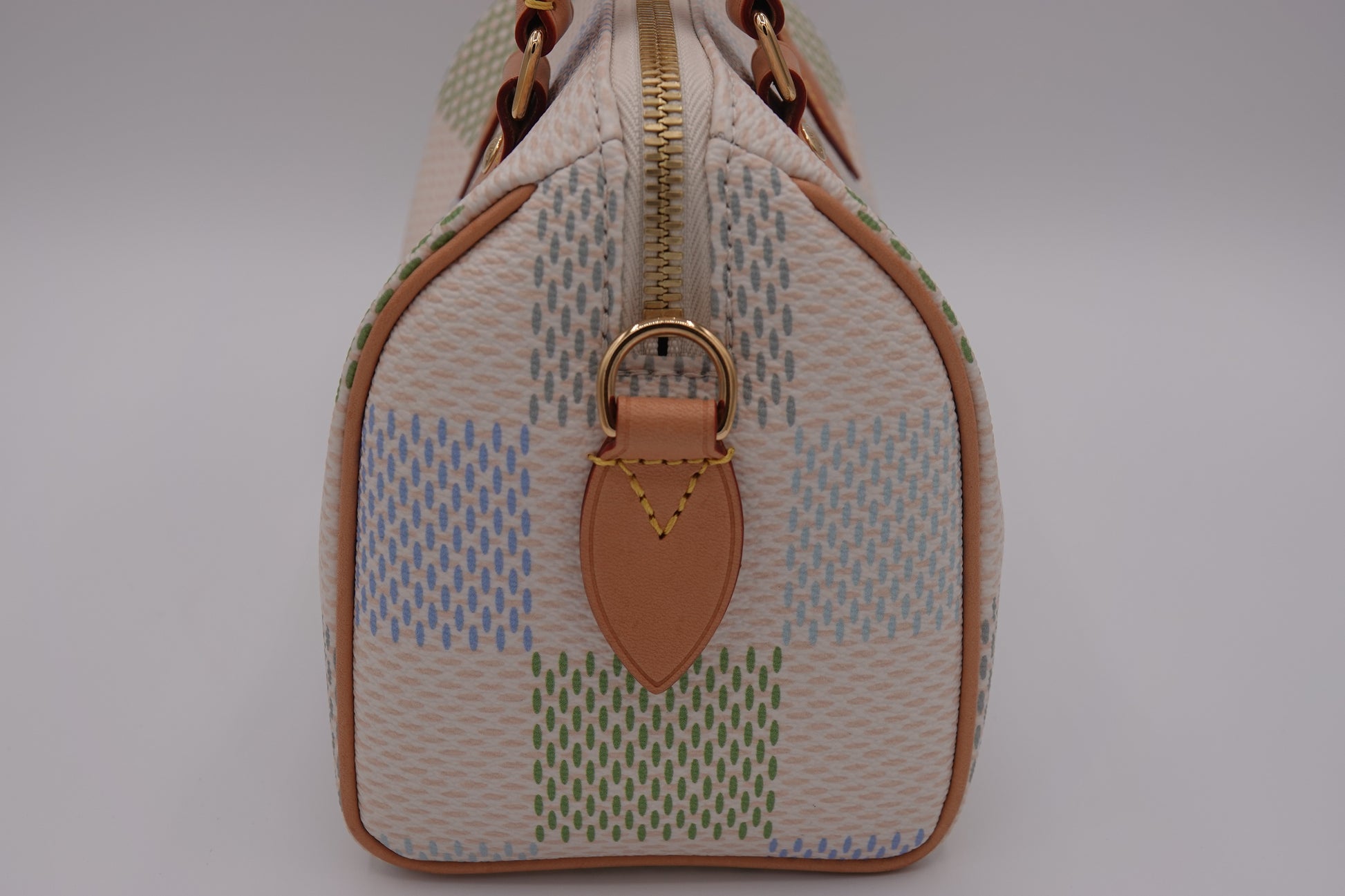 Designer handbag with patterned design and gold accents on a gray background