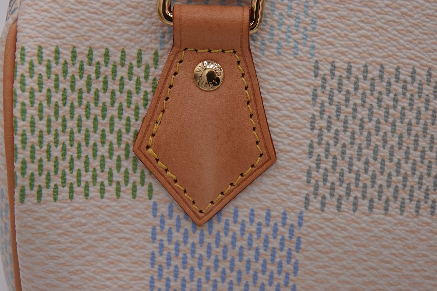 Close-up of a textured bag with a brown leather tag featuring stitching details.