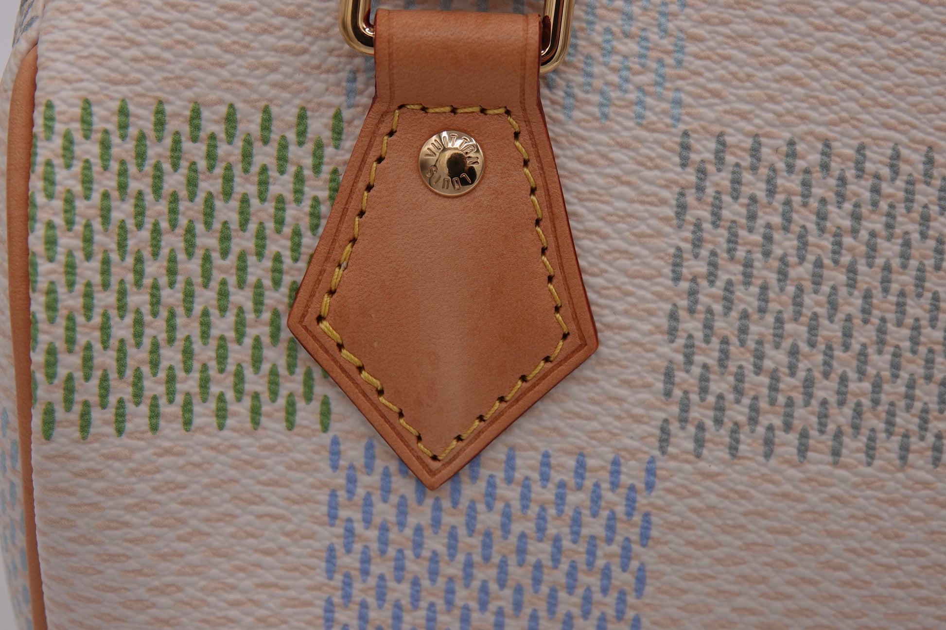 Close-up of a textured bag with a brown leather tag featuring stitching details.