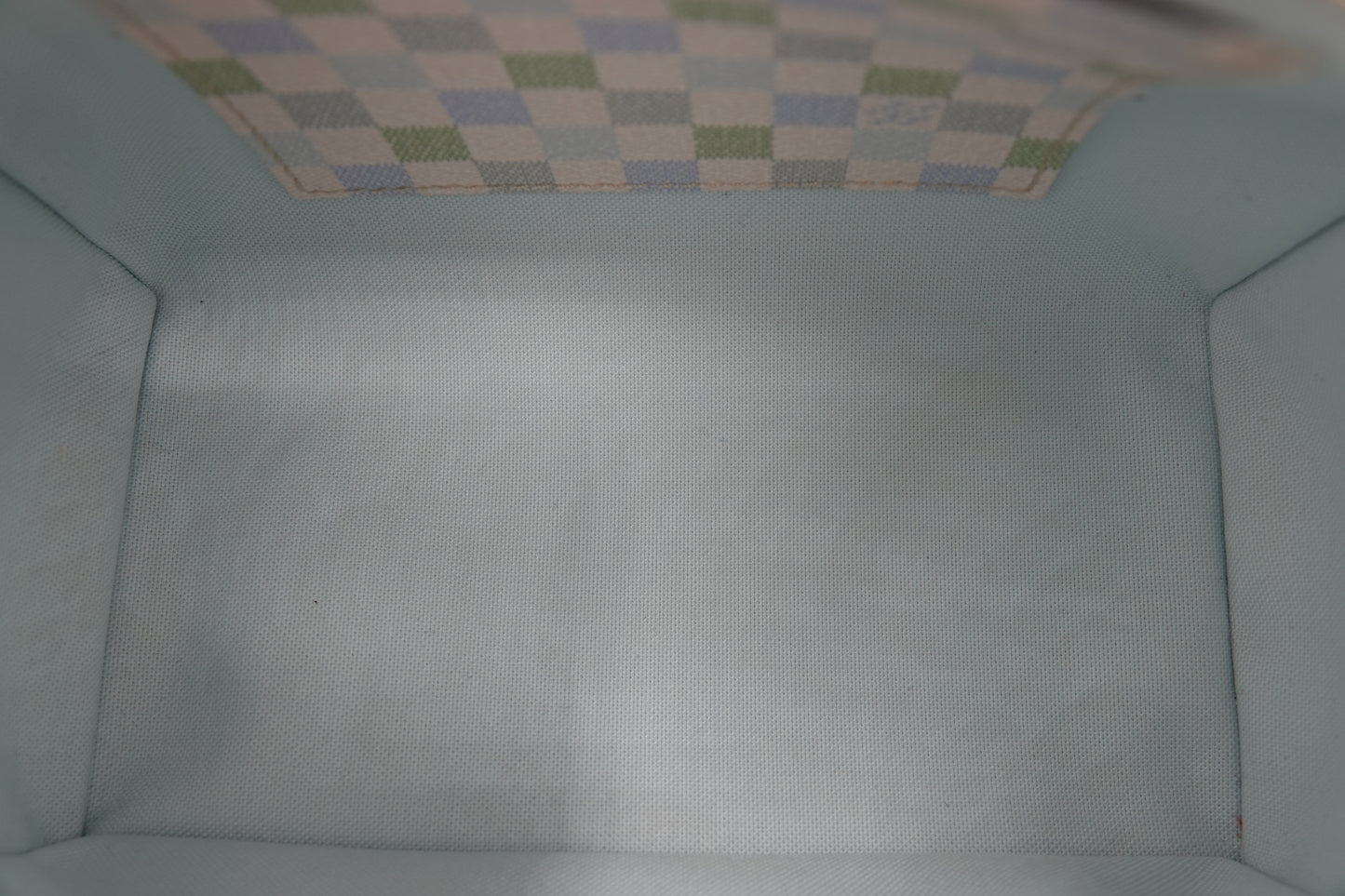 Close-up of a textured light blue fabric surface with a checkered pattern at the top.