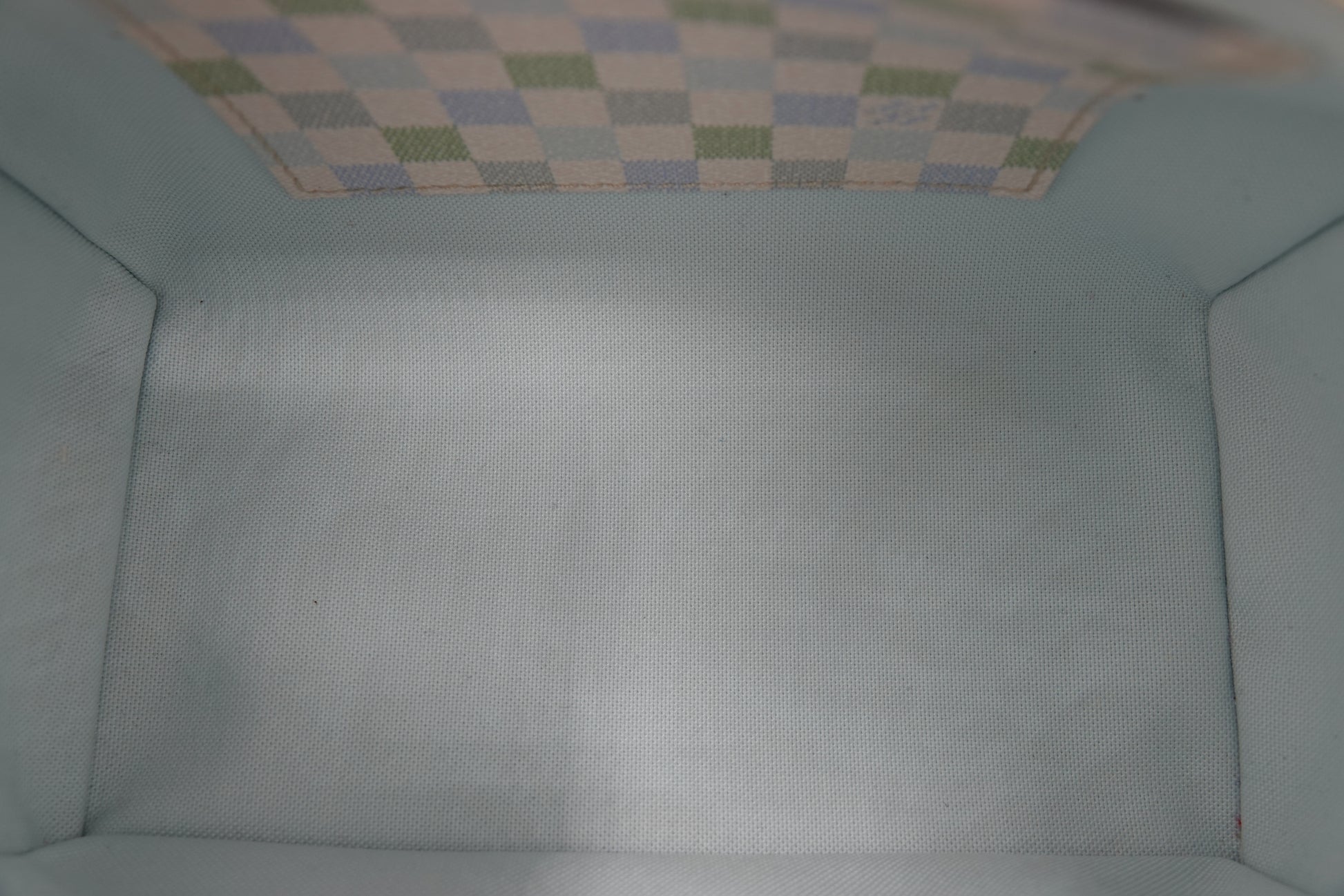 Close-up of a textured light blue fabric surface with a checkered pattern at the top.