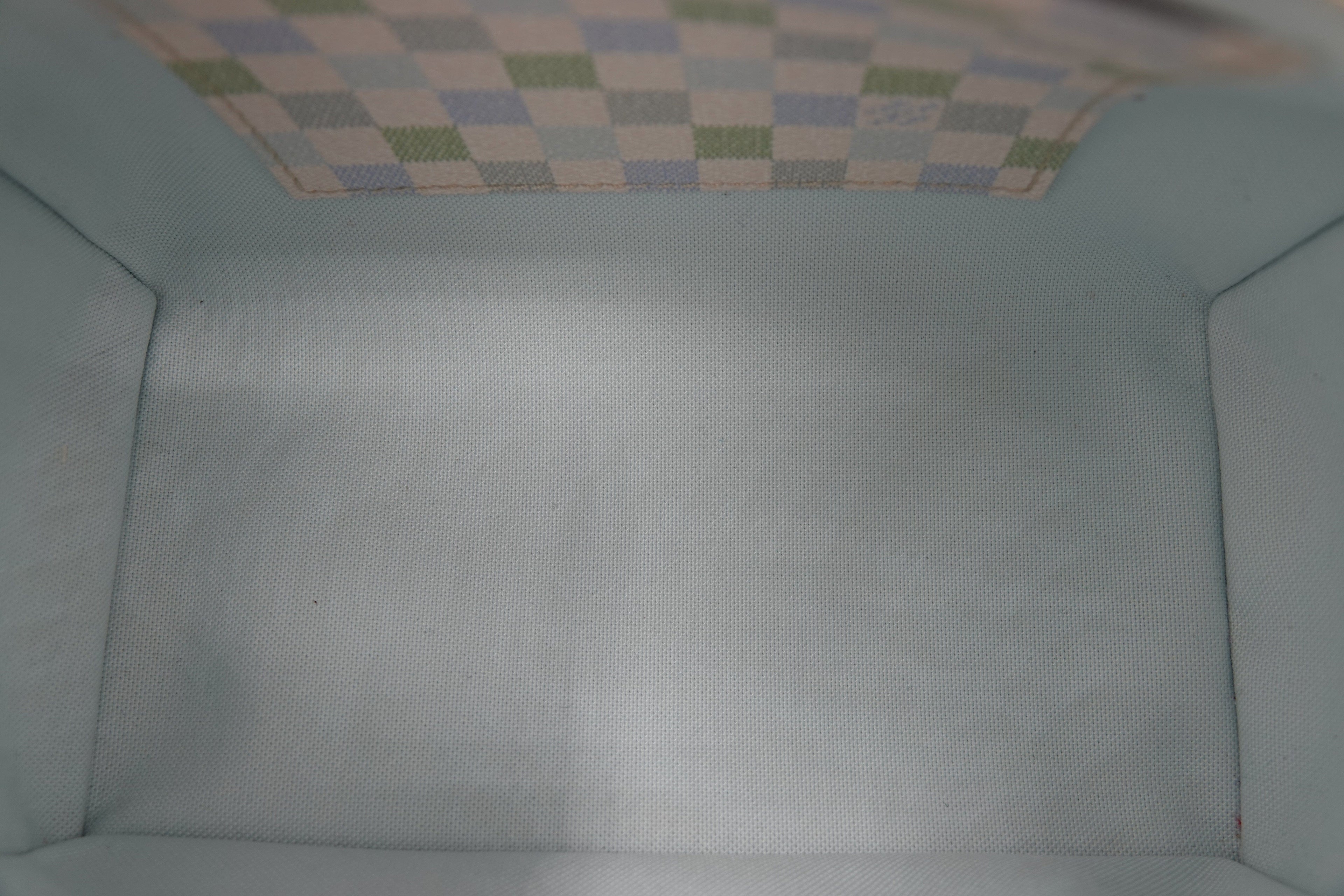 Close-up of a textured light blue fabric surface with a checkered pattern at the top.