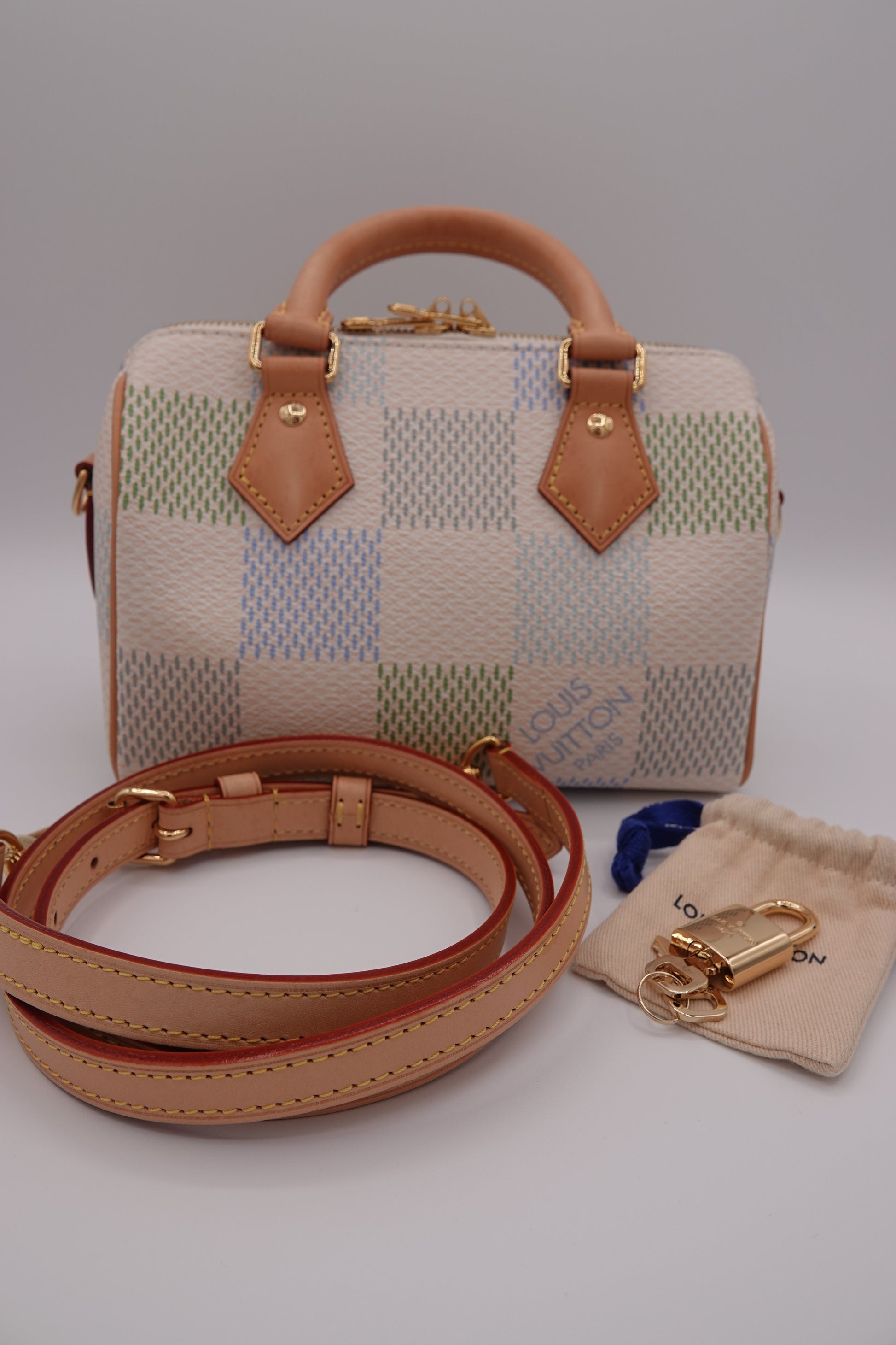 Designer handbag with checkered pattern and brown leather accents on a light gray background