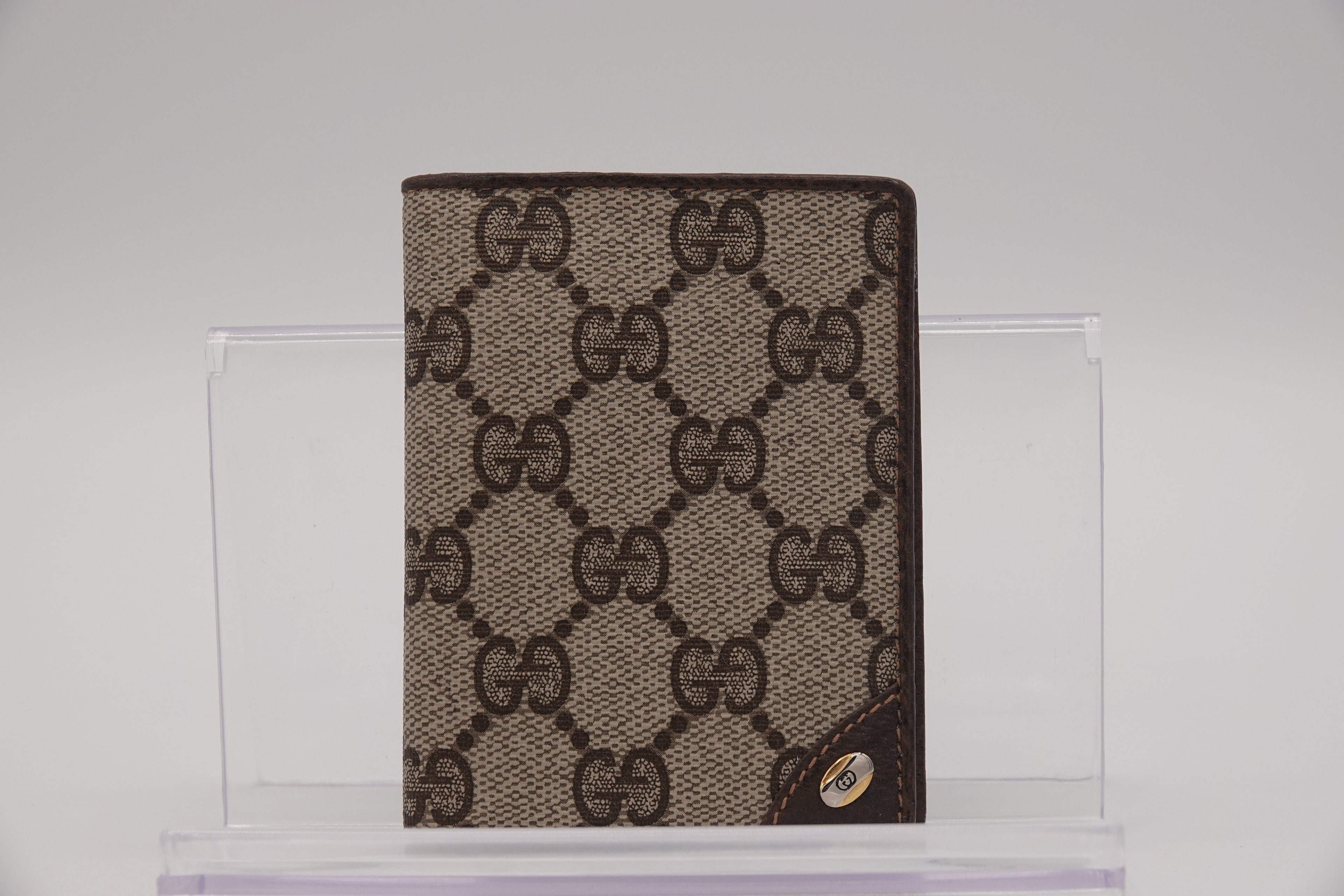 Gucci patterned wallet on a clear stand with a light gray background