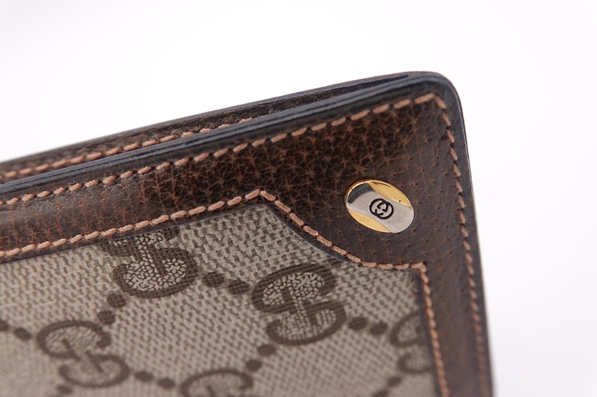 Close-up of a brown and beige patterned wallet with a logo on a white background