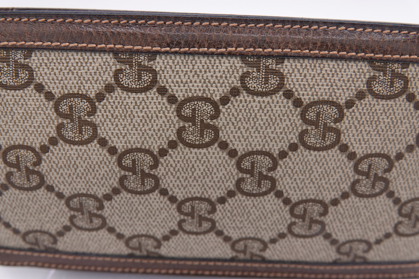 Close-up of a patterned fabric with a brand logo, likely Gucci, on a white background.