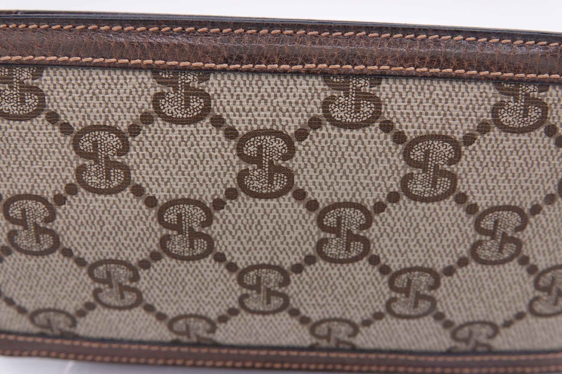 Close-up of a patterned fabric with a brand logo, likely Gucci, on a white background.