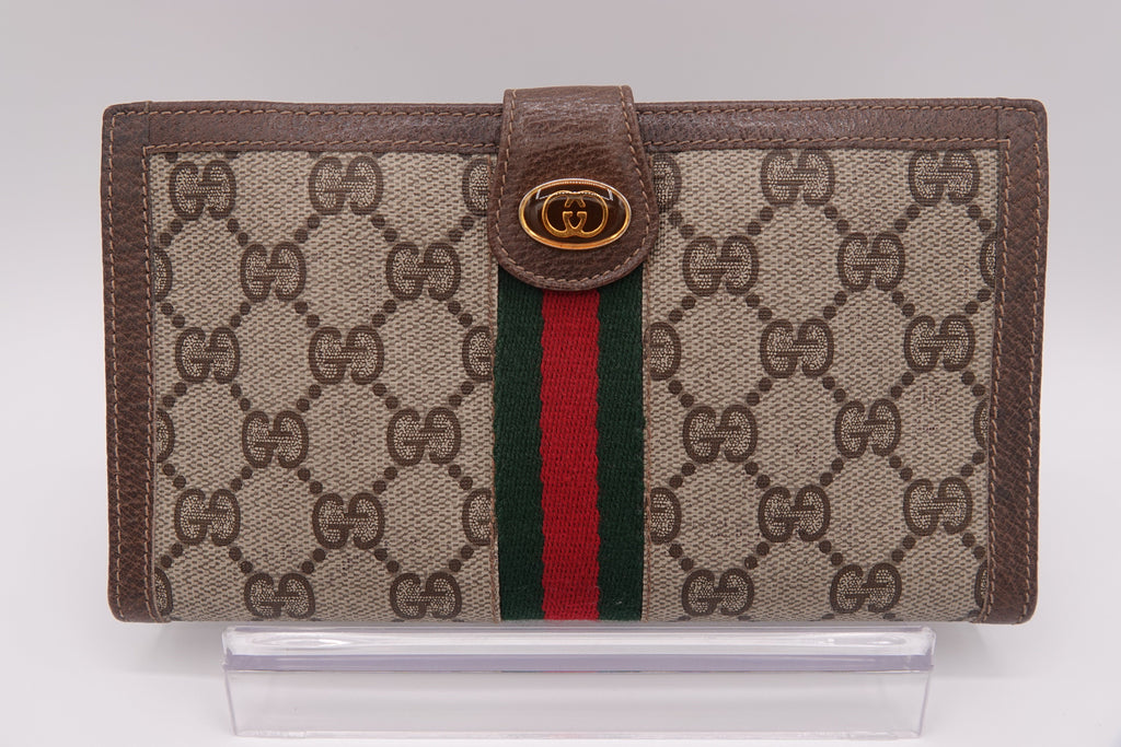 Gucci wallet with brown monogram canvas and red and green striped detail on a white background