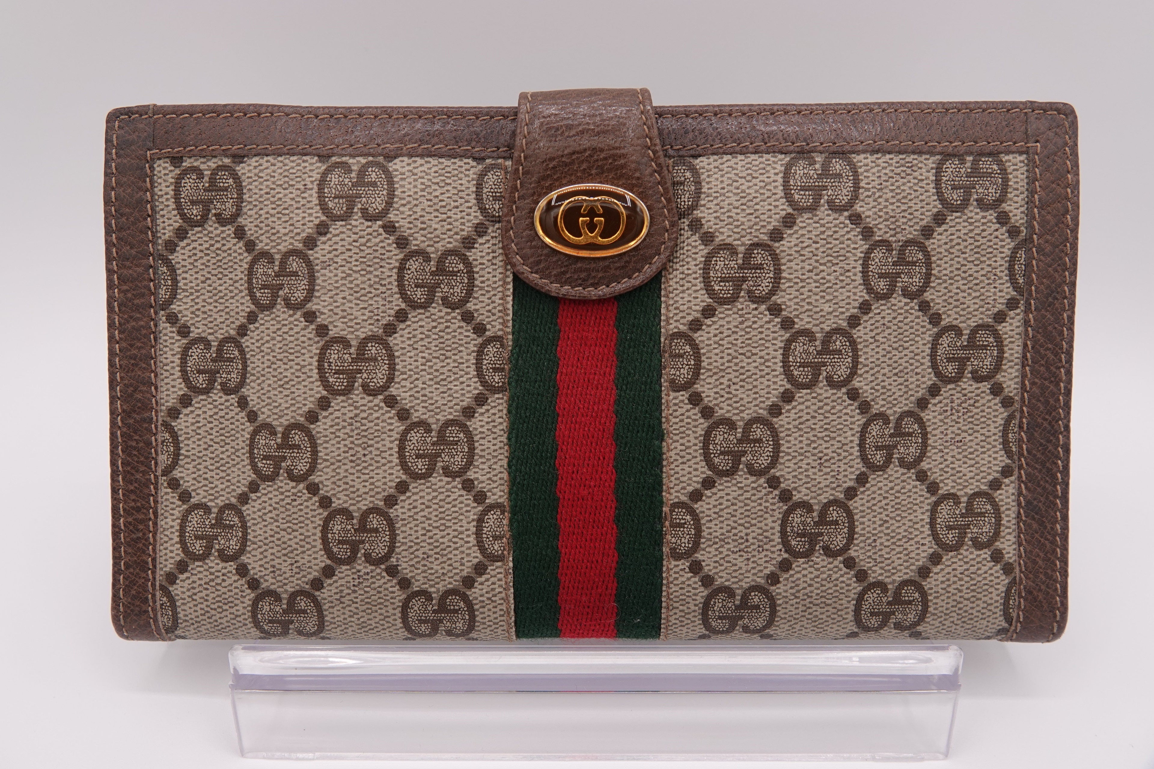 Gucci wallet with brown monogram canvas and red and green striped detail on a white background