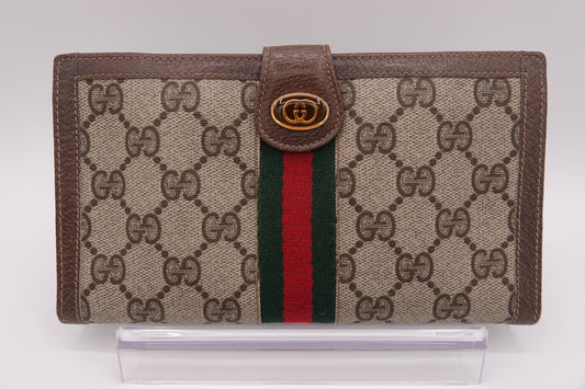Gucci wallet with brown monogram canvas and red and green striped detail on a white background