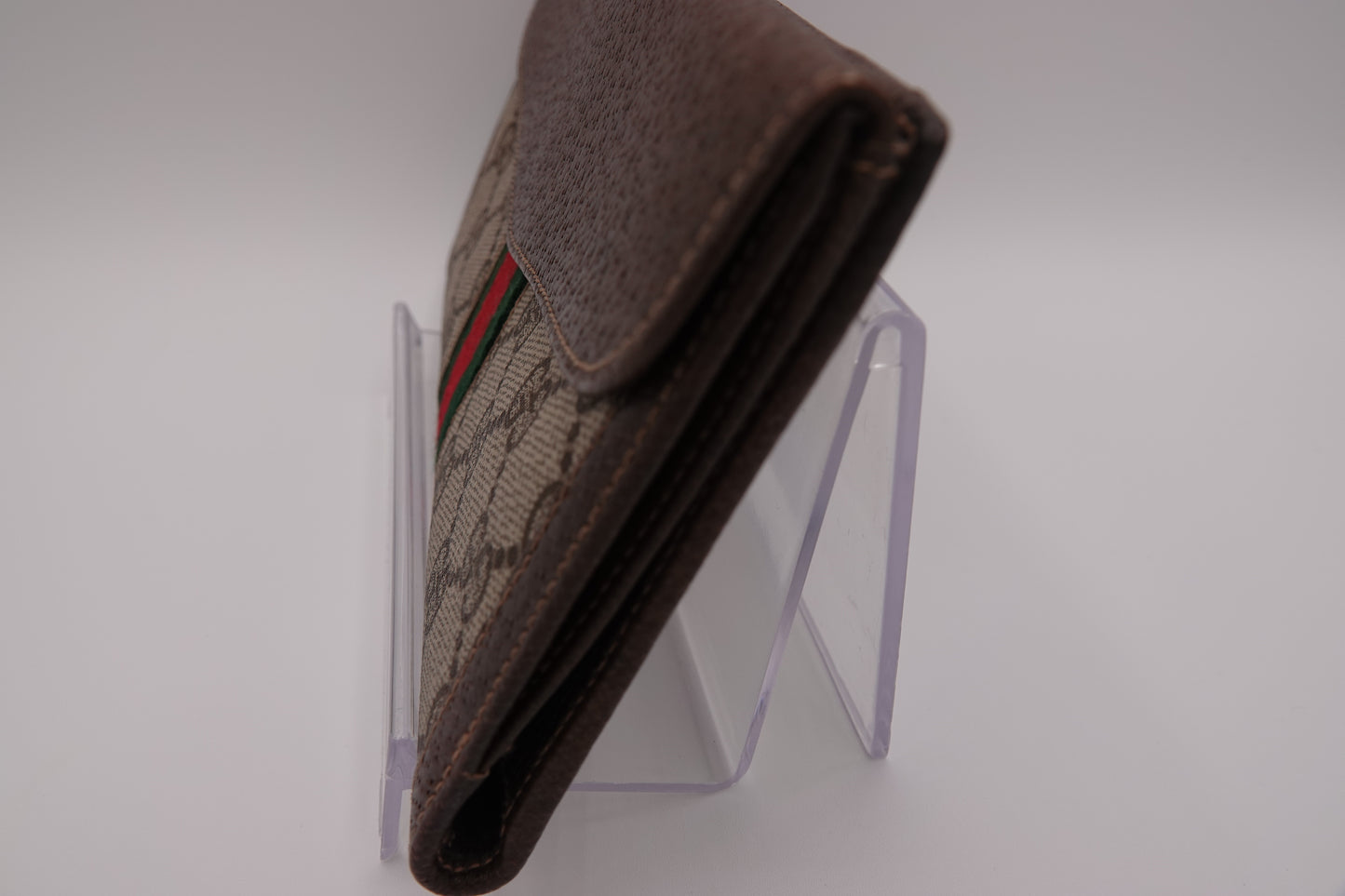 Brown wallet with a pattern on a clear stand against a white background