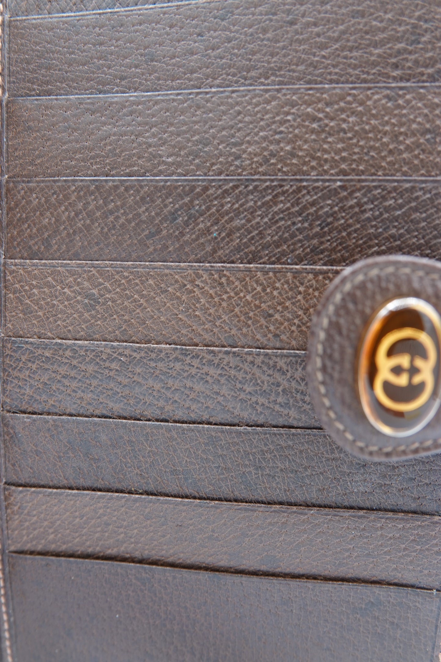 Close-up of a brown leather product with a gold logo on a matching brown background