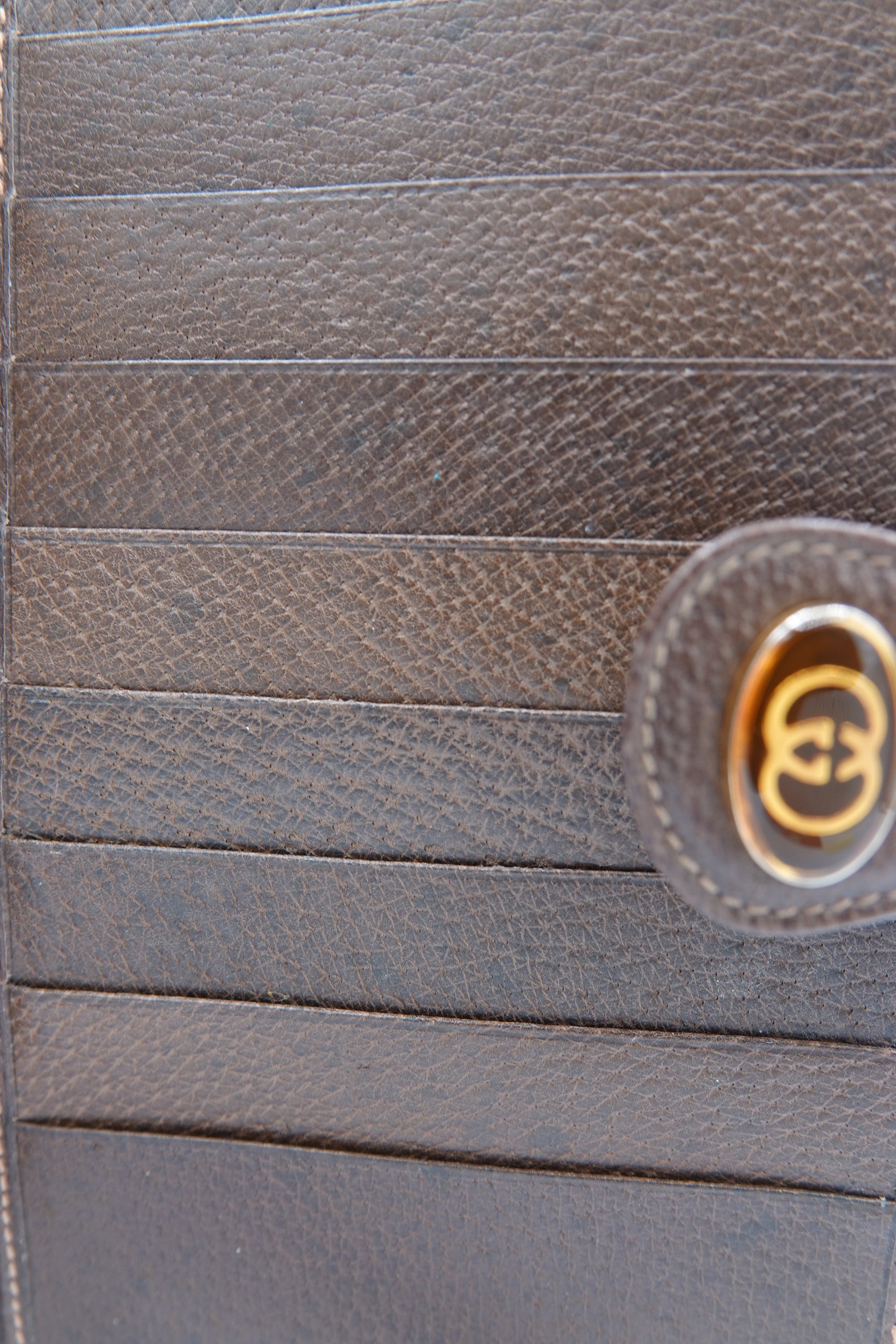 Close-up of a brown leather product with a gold logo on a matching brown background