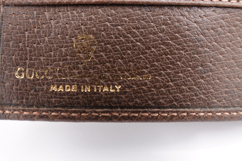 Close-up of a brown leather Gucci wallet with 'Made in Italy' text.