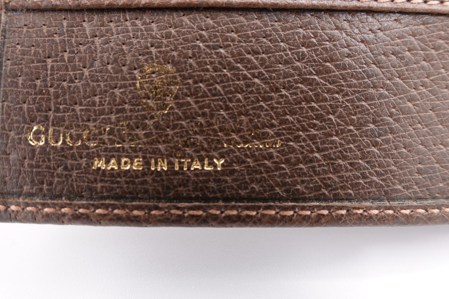 Close-up of a brown leather Gucci wallet with 'Made in Italy' text.