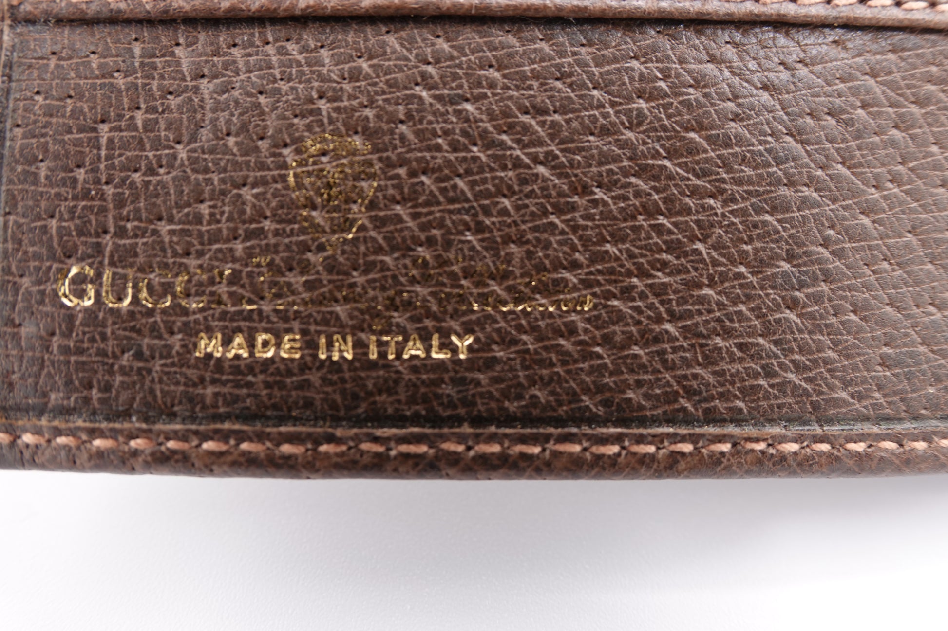 Close-up of a brown leather Gucci wallet with 'Made in Italy' text.