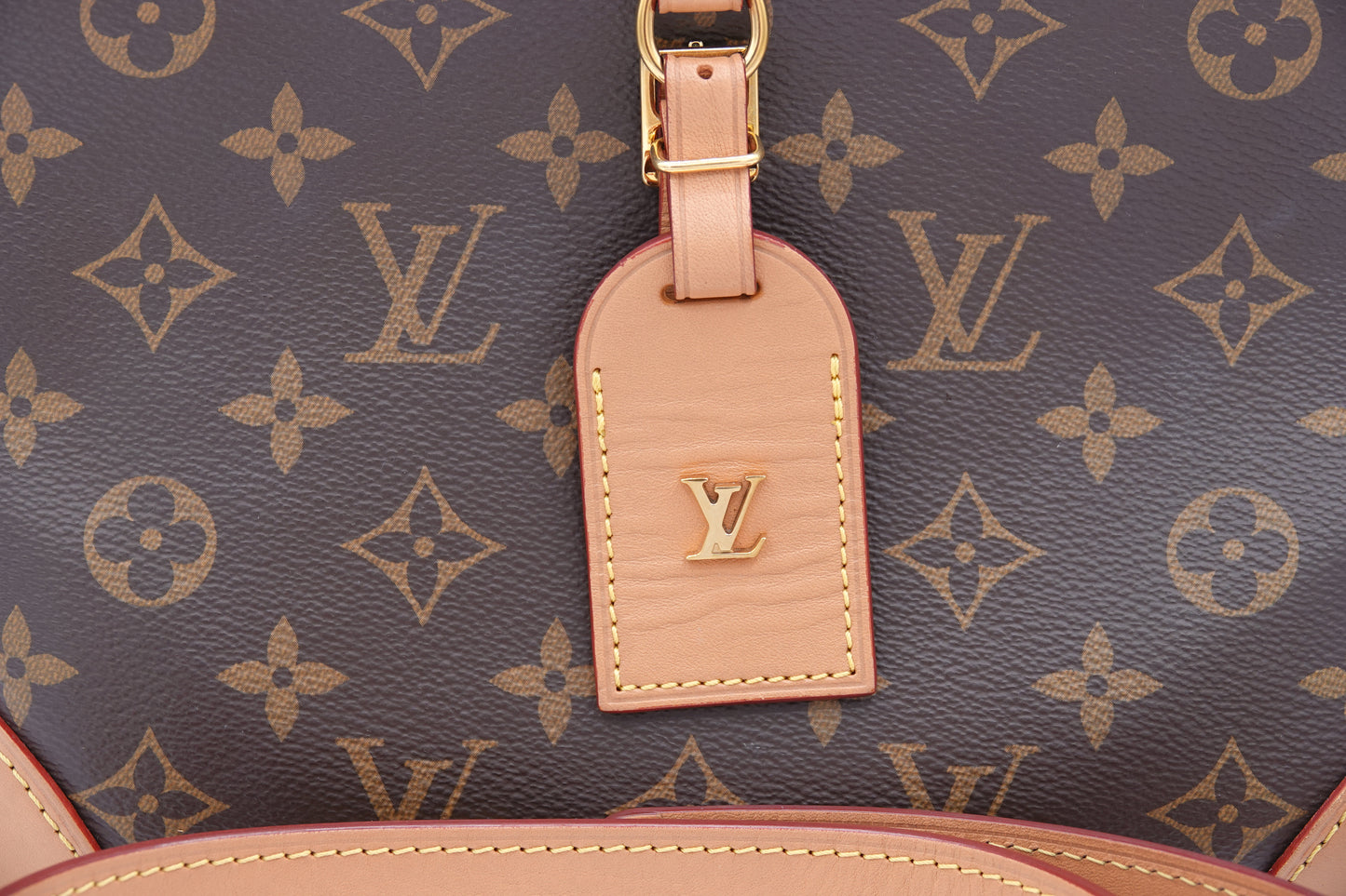Close-up of a Louis Vuitton bag with monogram pattern and pink tag.