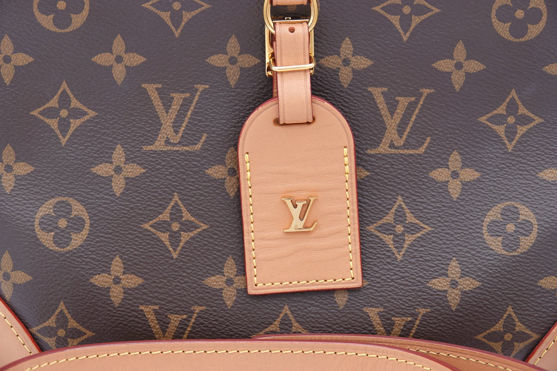 Close-up of a Louis Vuitton bag with monogram pattern and pink tag.