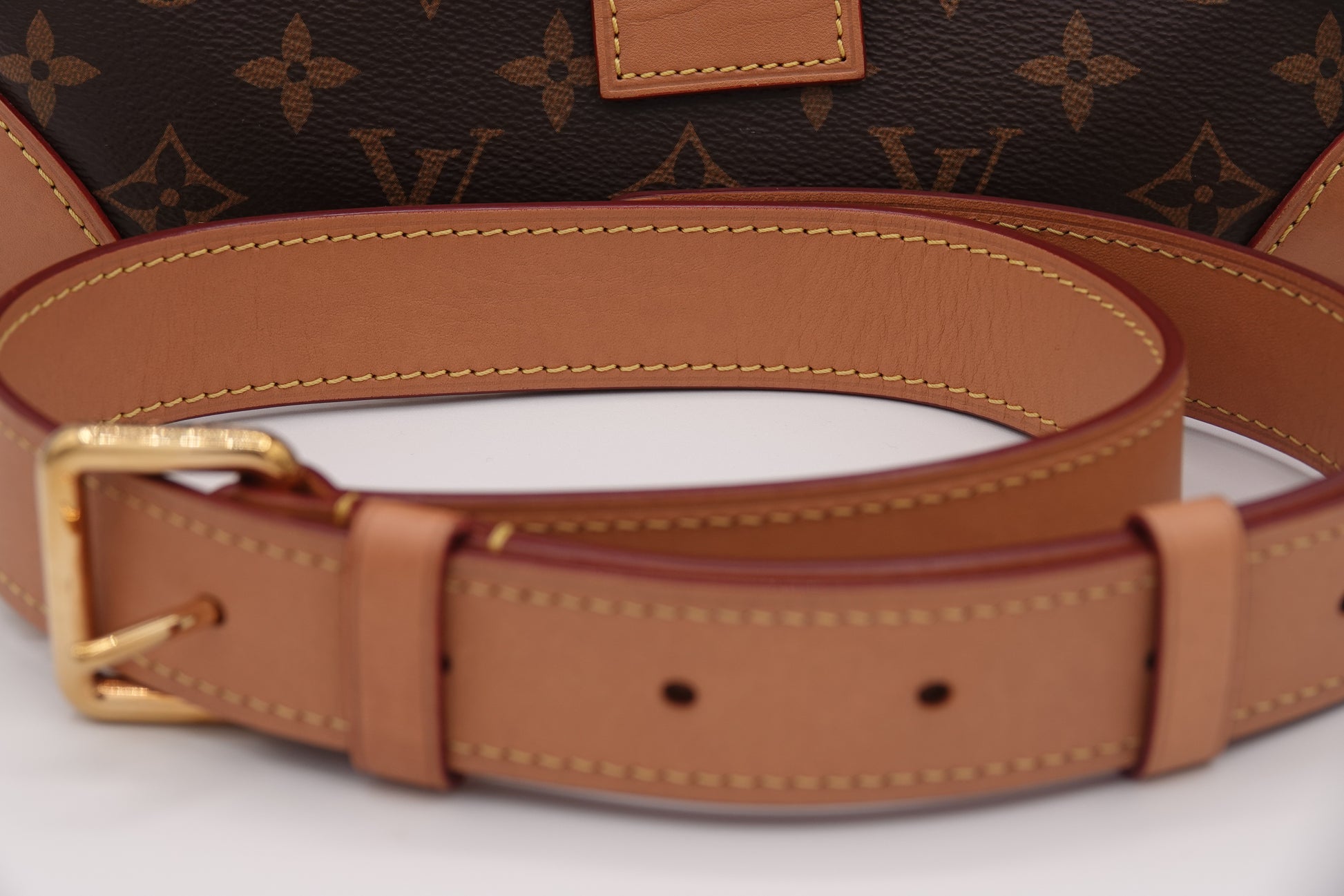Brown leather belt with gold buckle on a white background