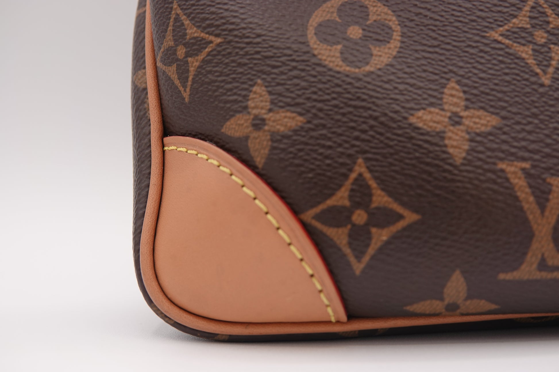 Close-up of a brown leather handbag with a distinctive pattern on a white background