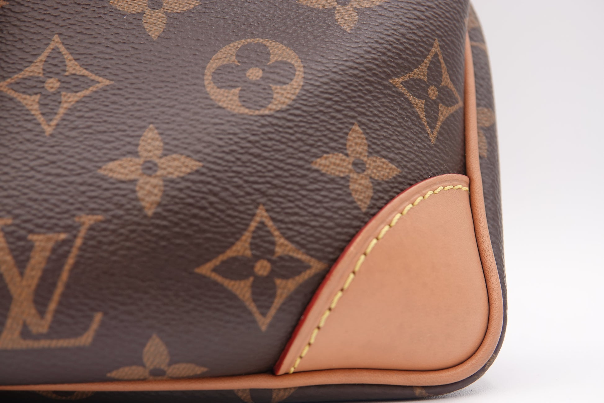 Close-up of a brown leather bag with a prominent logo pattern on a white background