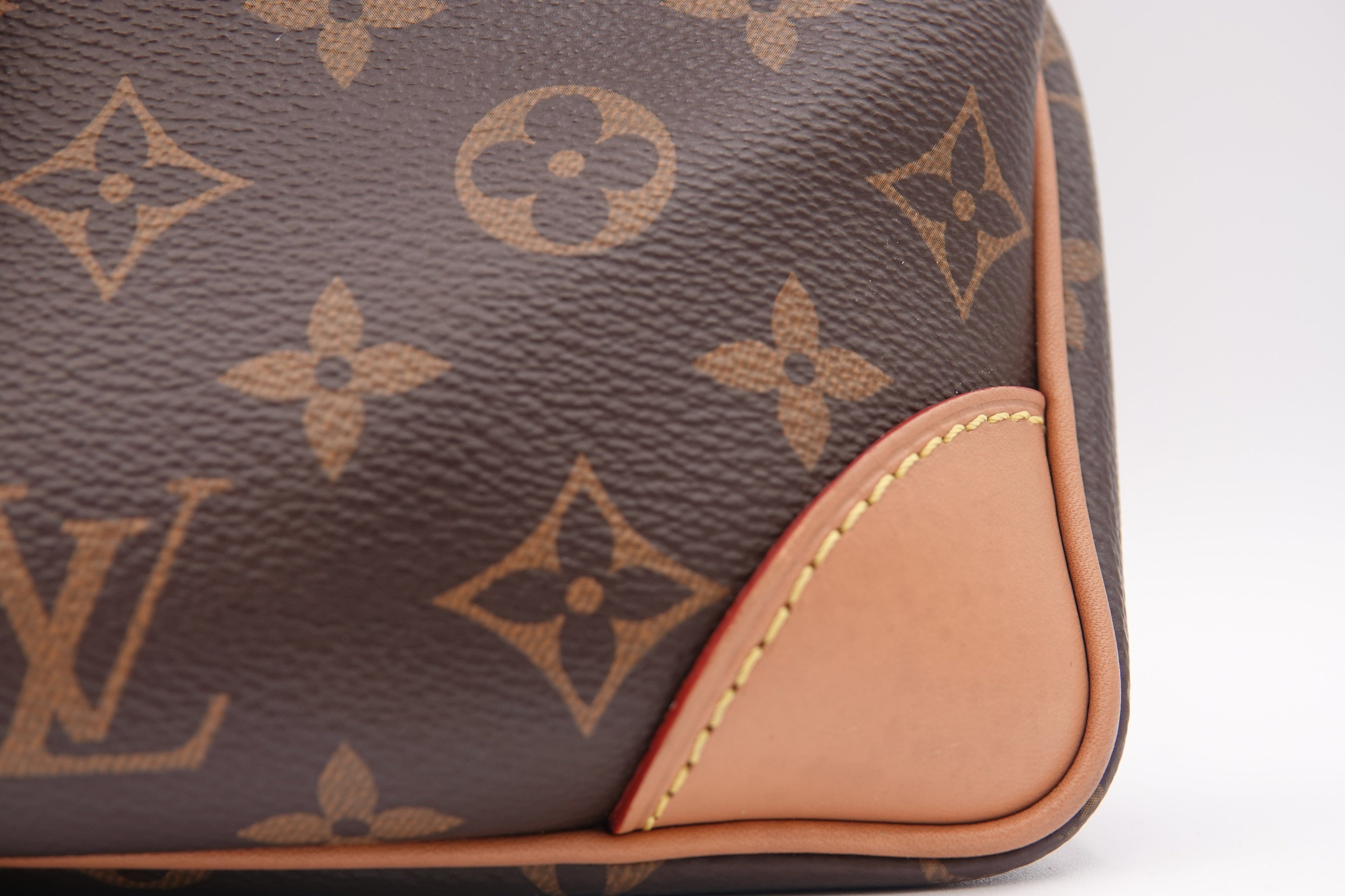 Close-up of a brown leather bag with a prominent logo pattern on a white background