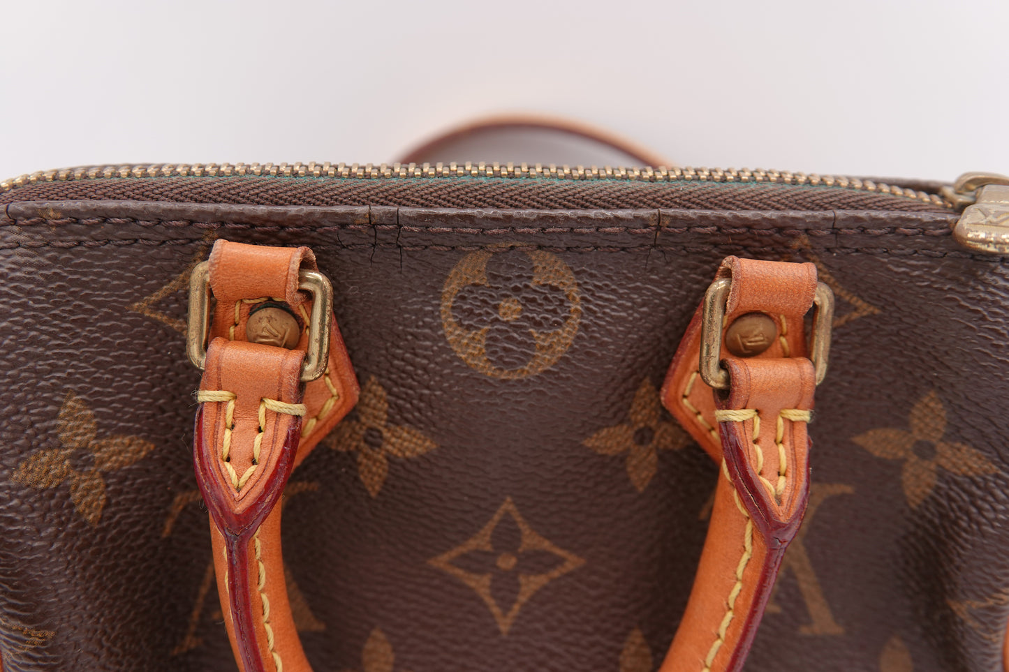 Close-up of a brown leather handbag with visible brand logo on a white background