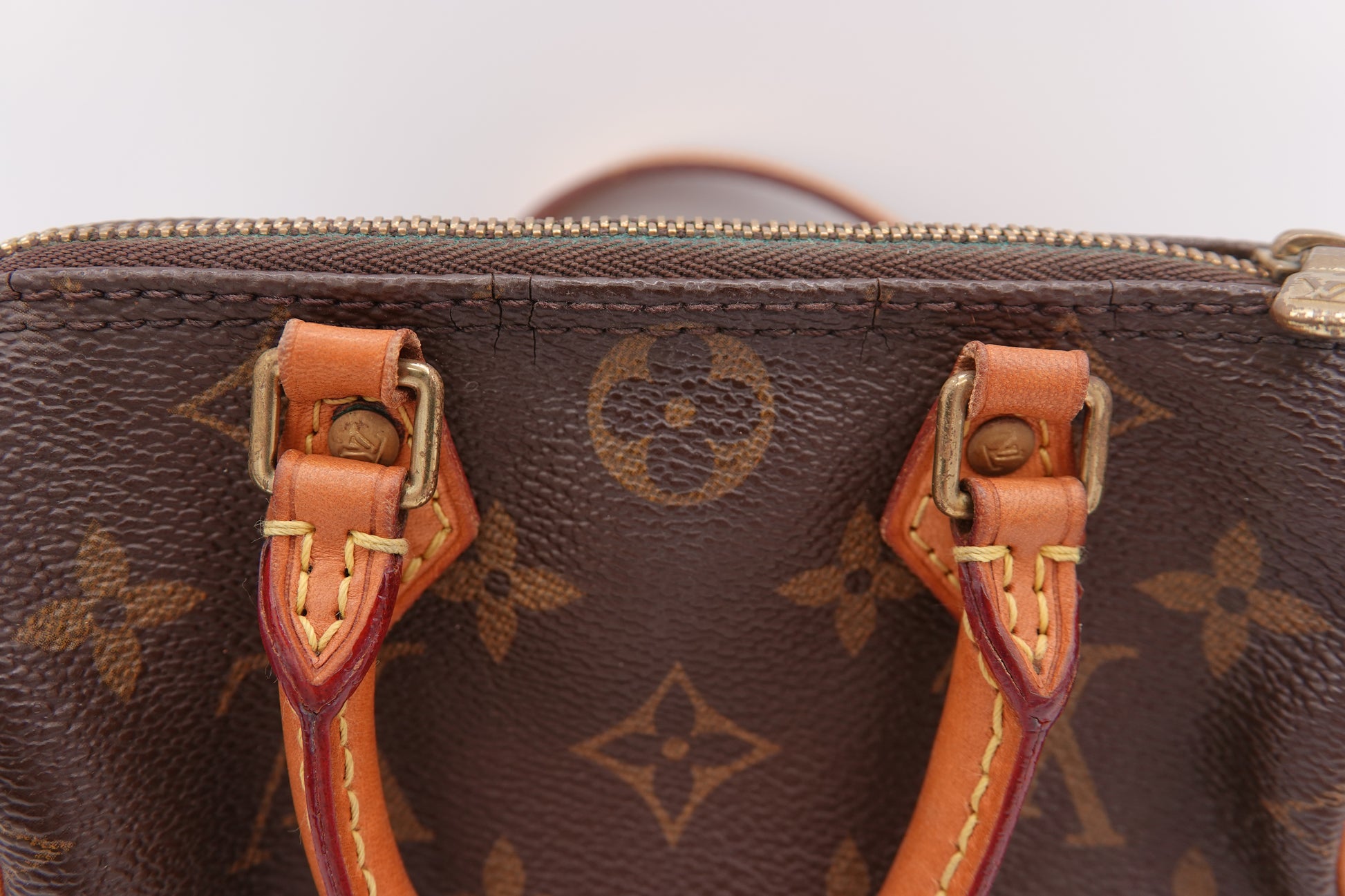 Close-up of a brown leather handbag with visible brand logo on a white background