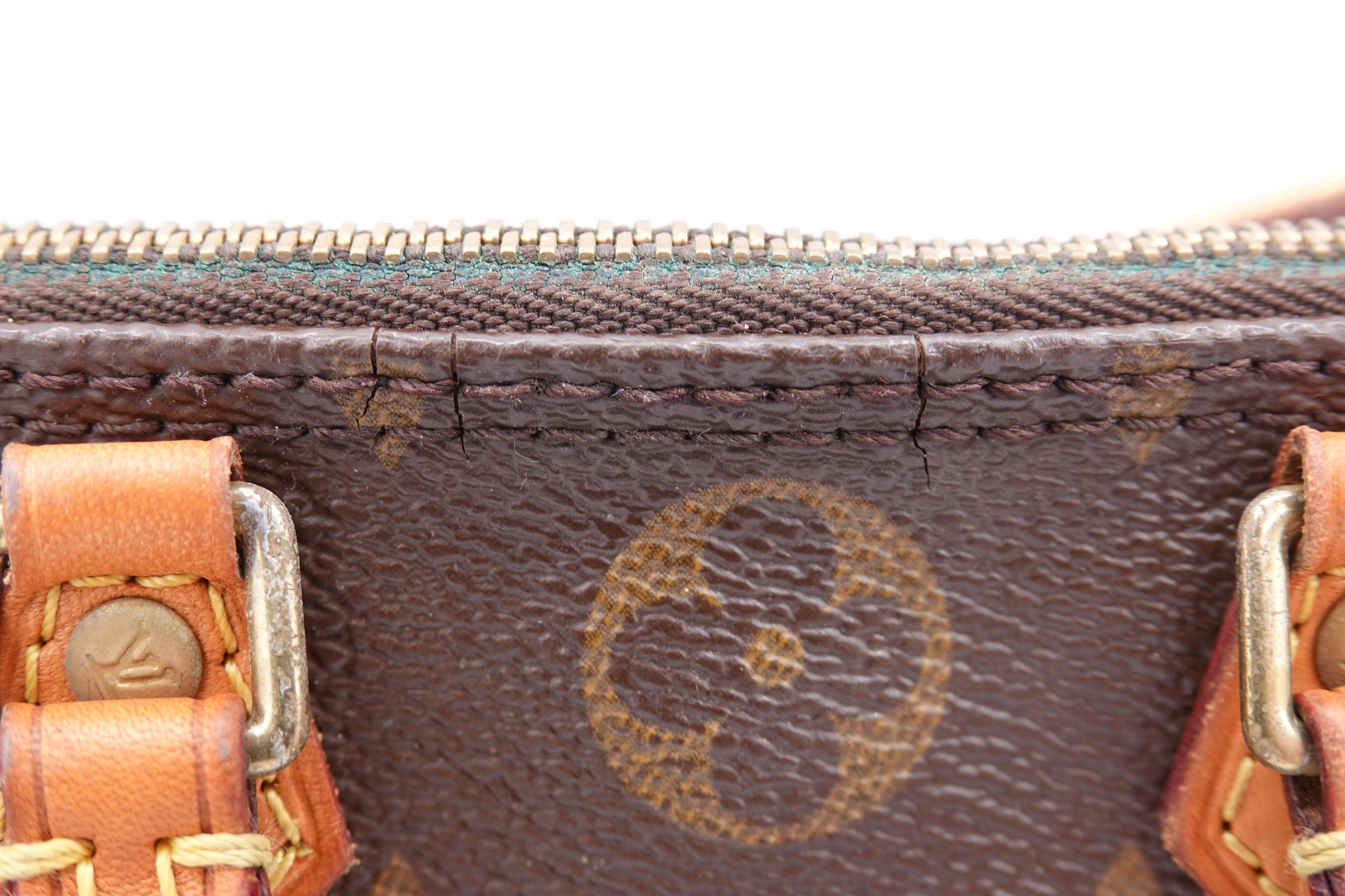 Close-up of a brown leather bag with gold hardware and visible brand logo.
